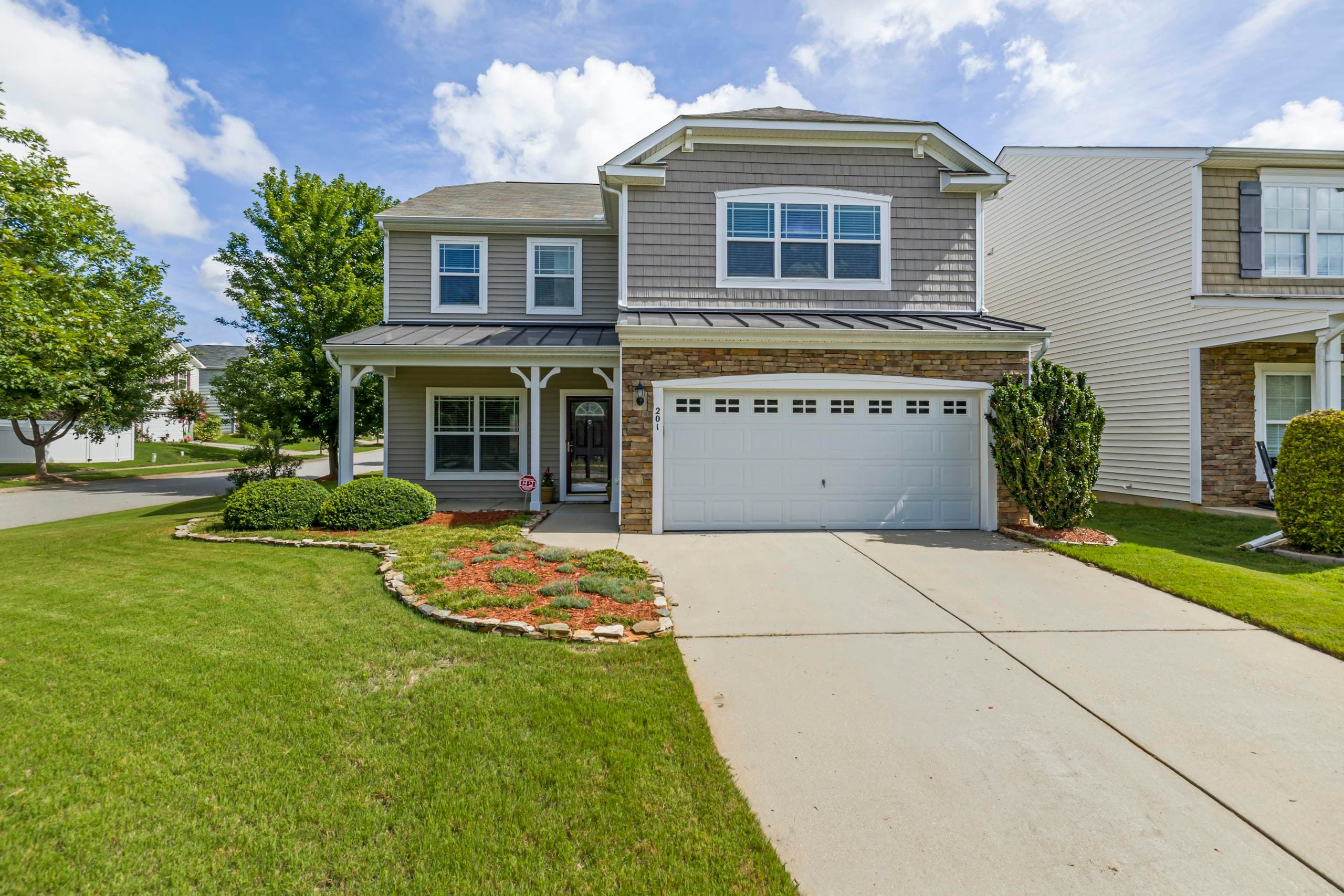 Charming suburban house facade with a tidy front yard, located in a residential neighborhood.